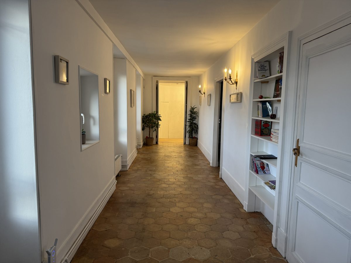 Le couloir après travaux : tommettes hexagonales, appliques murales et bibliothèque encastrée