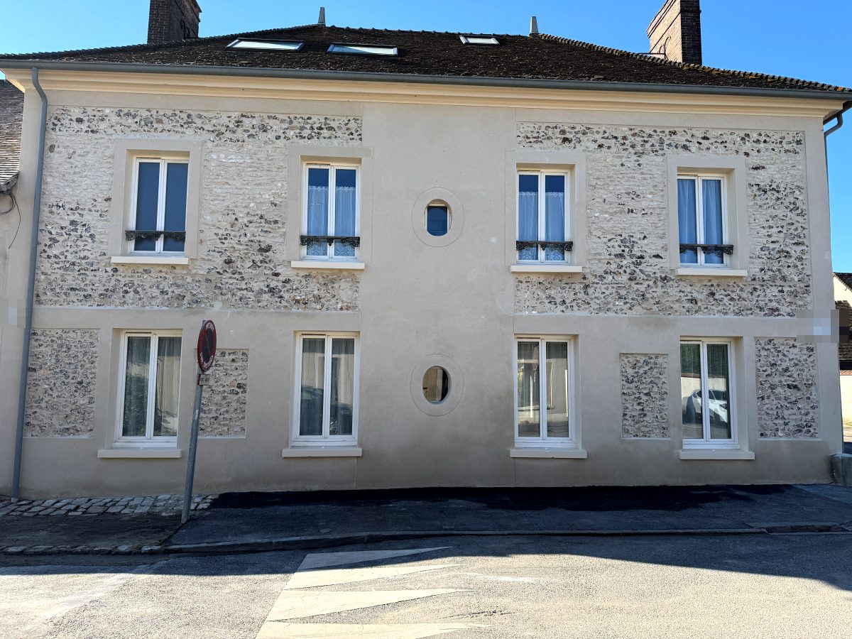 Façade côté rue restaurée, panneaux de silex et encadrements de pierre