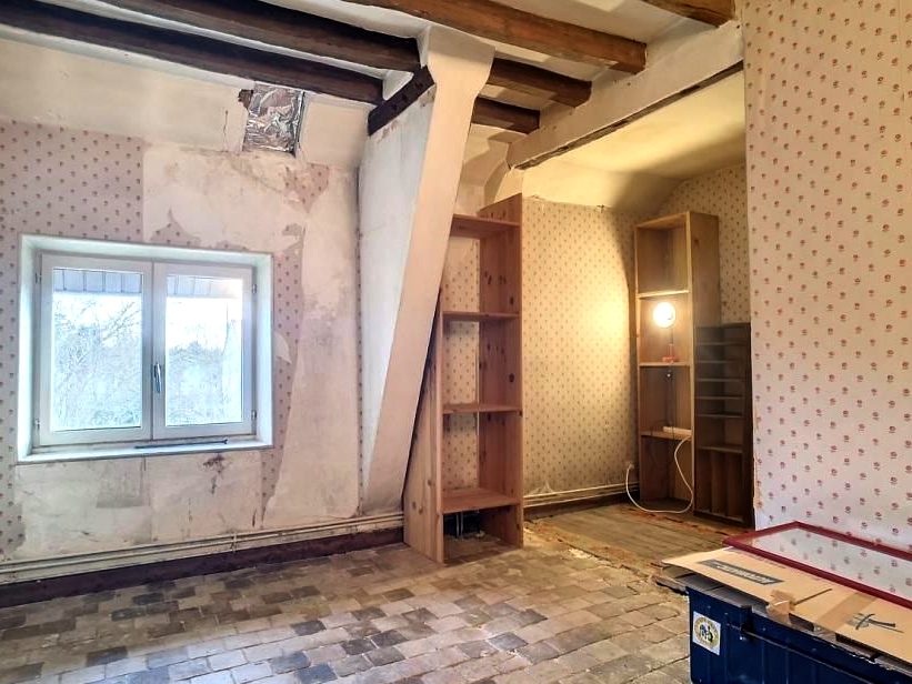 Chambre avec papier peint à pois, poutres apparentes et tommettes