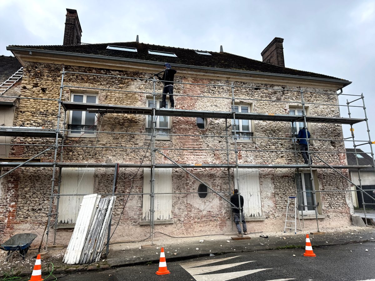 La façade côté rue sous échafaudage, enduit retiré, pierre et brique à nu